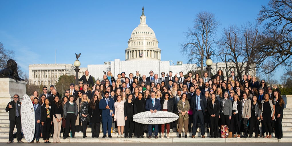 Group of Surfrider Foundation volunteers in Washington, DC, for Environmental lobby days, holding a signed surfboard to show support.